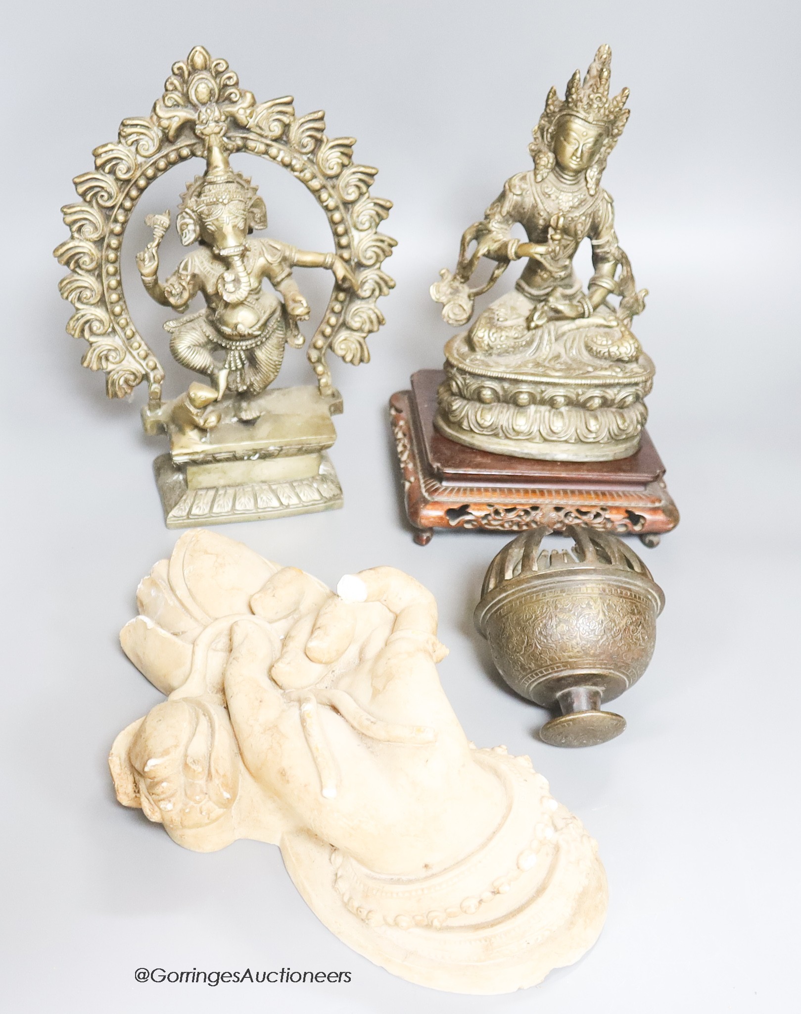 Two reproduction brass figures of Indian deities, a bell, a carved stand and a plaster plaque, tallest 26cm